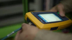 Fluke LinkIQ industrial tester being used to test M12 connector cable on factory floor