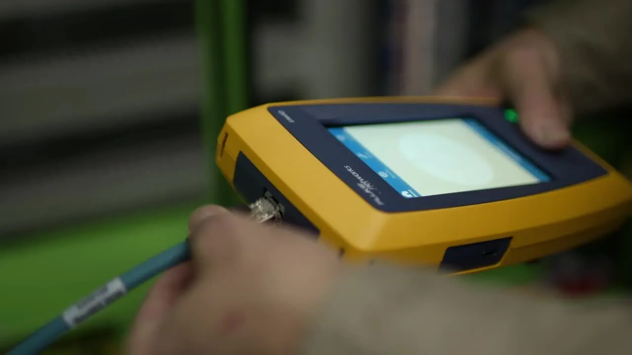 Fluke LinkIQ industrial tester being used to test M12 connector cable on factory floor