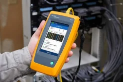 Fluke LinkIQ industrial tester being used to test M12 connector cable on factory floor